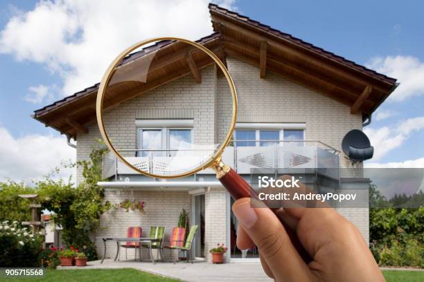 Persons Hand Holding Magnifying Glass Over Luxury House Stock Photo - Download Image Now