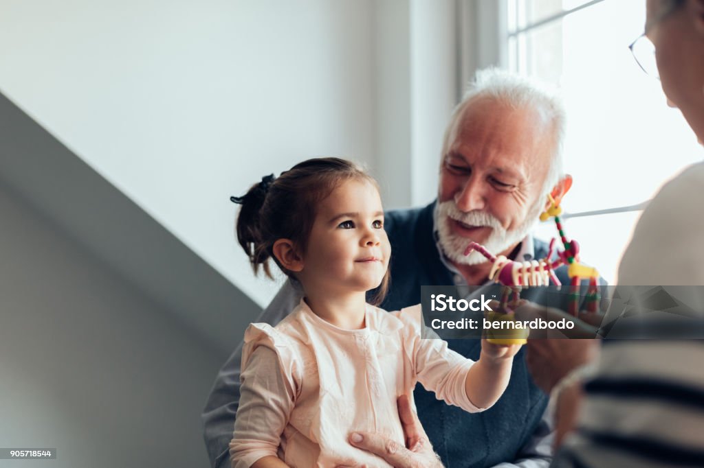 My grandparents are the best ! Young girl playing with a new toy Grandfather Stock Photo