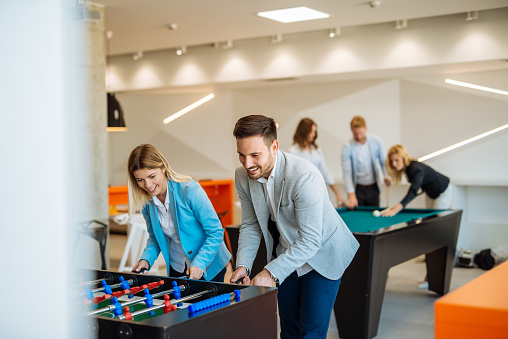 Coworkers playing a foosball table in an office.