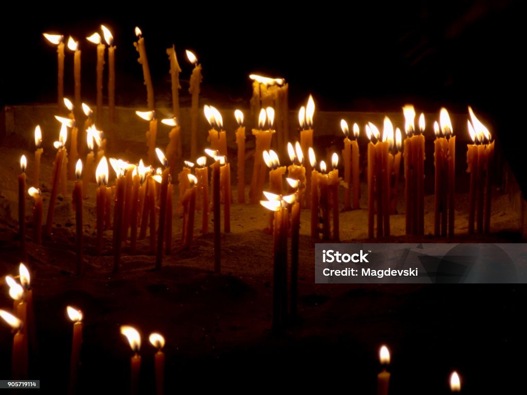 burning candles in a sand on a candle stand in the church burning candles on a candle stand in the church Ancient Stock Photo