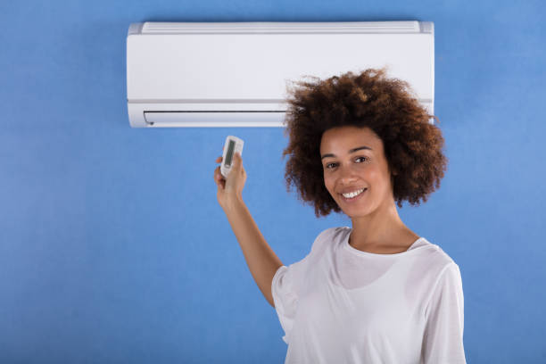 istock Woman Adjusting Air Conditioner With Remote Control 905726864