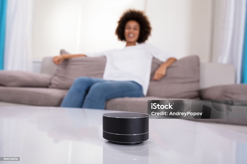 Close-up Of Wireless Speaker On Table Close-up Of Wireless Speaker In Front Of Woman Sitting On Sofa Amplifier Stock Photo