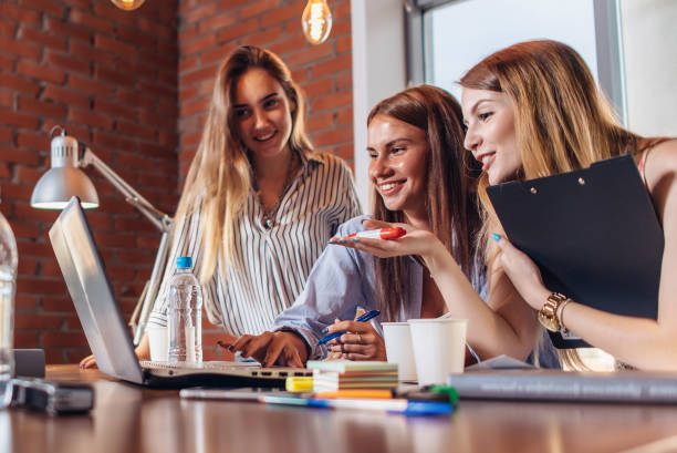 istock Three positive businesswomen working on laptop discussing joint business project 905730654