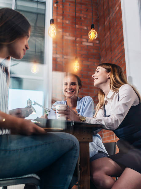 tres mujeres felices tomando café, charlando y charlando en la oficina - coffee buzz fotografías e imágenes de stock