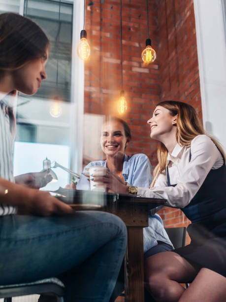 trzy szczęśliwe kobiety pijące kawę, rozmawiające i plotkujące w biurze - coffee buzz zdjęcia i obrazy z banku zdjęć