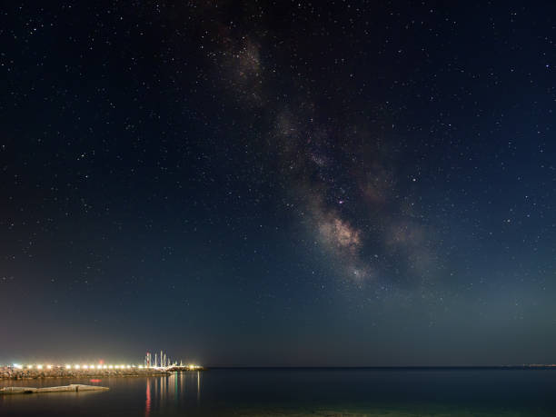 istock Panoramic Milky Way galaxy and young moonset. Milky Way galaxy over the seacoast with moonset, small harbor on the left side 905735854