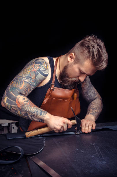 istock Craftsman working with leather cutting leather outlines for his new production 905742404