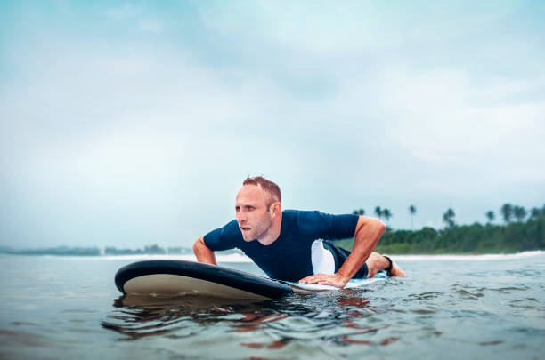 istock Surfer man floats on surf board, waits a waves 905746750