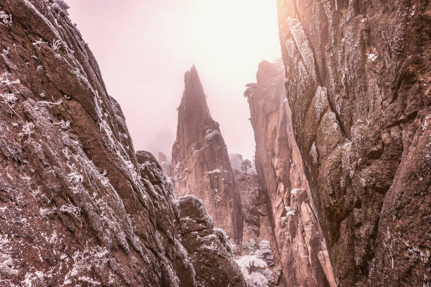 Cliffs in Huangshan National park at foggy winter evening. China.