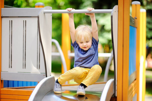 Little boy having fun on outdoor playground/on slide Little boy having fun on outdoor playground/on slide. Summer active sport leisure for kids swing play equipment stock pictures, royalty-free photos & images
