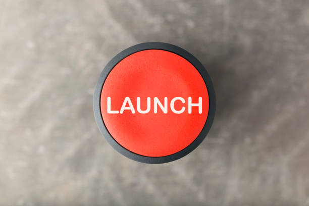 Overhead of Red Launch Push Button Over Blurred Gray Background Overhead of a red 'launch' push button over a blurred gray background launch tower stock pictures, royalty-free photos & images