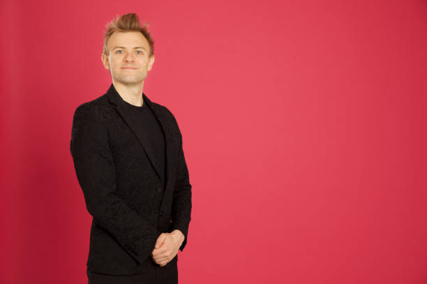 Portrait of smiling businessman gesturing heart shape against red background