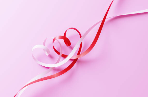 Valentines Day concept. Heart shaped ribbons tangled on pink background. Horizontal composition with Selective focus and copy space.