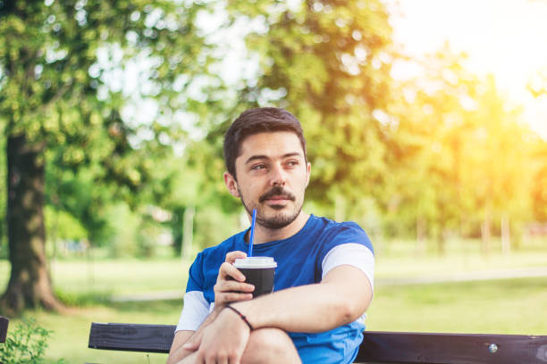 istock Young man relaxing at park with favorite coffee. 905771166
