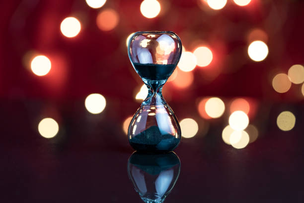istock Hourglass or sandglass on red dark background with decoration light bokeh using as Party always end concept 905772144
