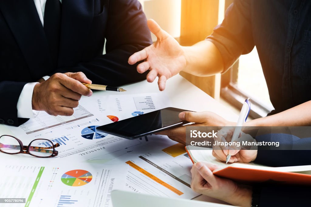 Business people using pen,tablet,notebook are planning a marketing plan to improve the quality of their sales in the future. Business people using pen, tablet, notebook are planning a marketing plan to improve the quality of their sales in the future. Financial Advisor Stock Photo