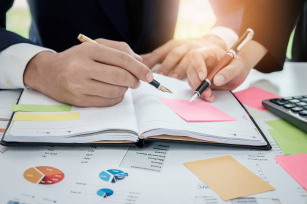 istock Young businessman and partner hands holding pen pointing graph c 905778114