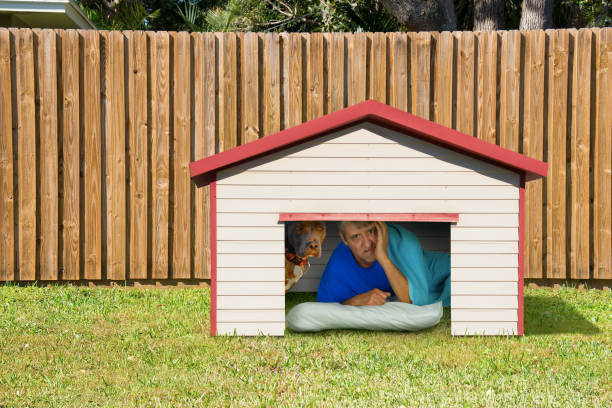 Husband or boyfriend man sleeping in the doghouse because of domestic problems stock photo