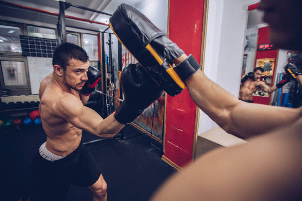 Training time Young muscular man doing boxing exercise with trainer boxercise stock pictures, royalty-free photos & images