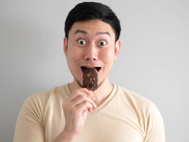 istock Funny face man eat chocolate vanilla ice pop. 905799352