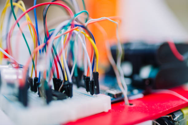 Macro photo of a little embedded systems breadboard with attached cables. White small breadboard with small electronics components and sensors on it.