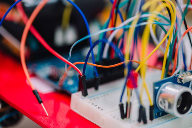 istock Macro photo of a little embedded systems breadboard with attached cables. White small breadboard with small electronics components and sensors on it. 905818872