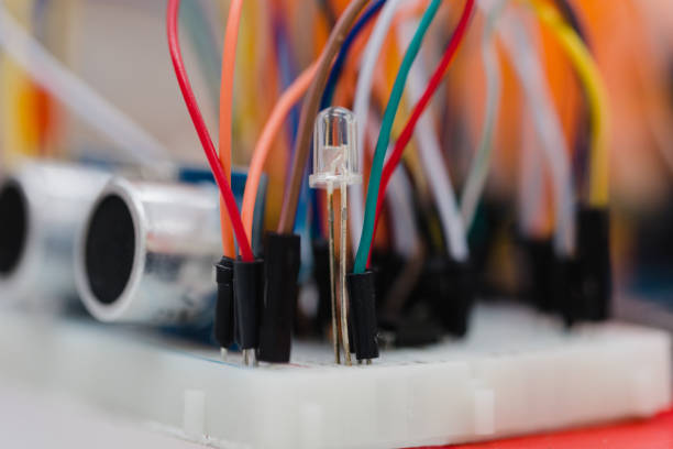 istock Macro photo of a little embedded systems breadboard with attached cables. White small breadboard with small electronics components and sensors on it. 905818880
