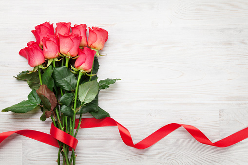 Valentines day greeting card with red roses on wooden background. Top view with space for your greeting