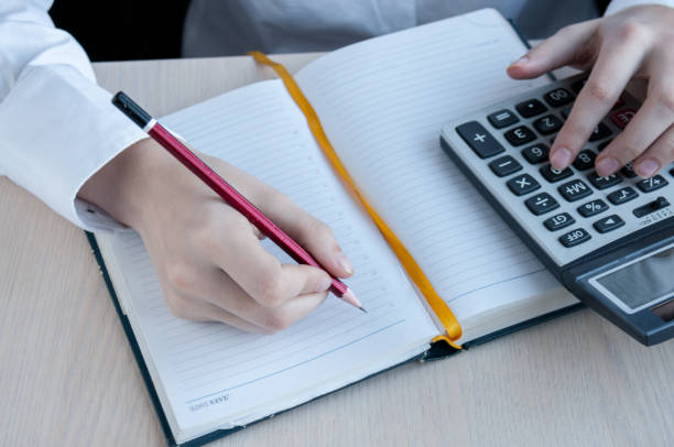 istock The girl counts calculator and writes to notebook at the table 905827068