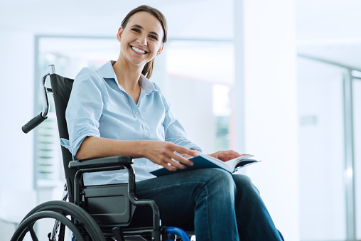 Smiling young woman in wheelchair looking at camera