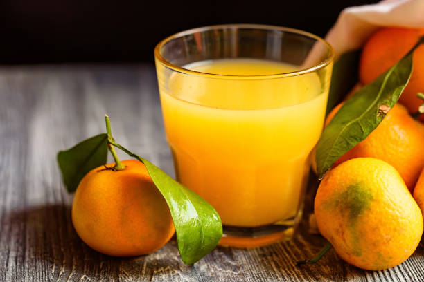 istock Glass of fresh juice and mandarins on table 905849824