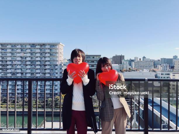 Young Man And Woman Hugging Red Heart Balloon On Urban Rooftop Stock Photo - Download Image Now