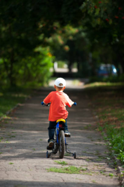 istock Little child on a bicycle at asphalt road in park. 905859628