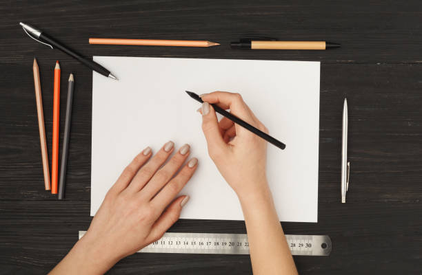 istock Woman's hands drawing on white paper, top view 905862686