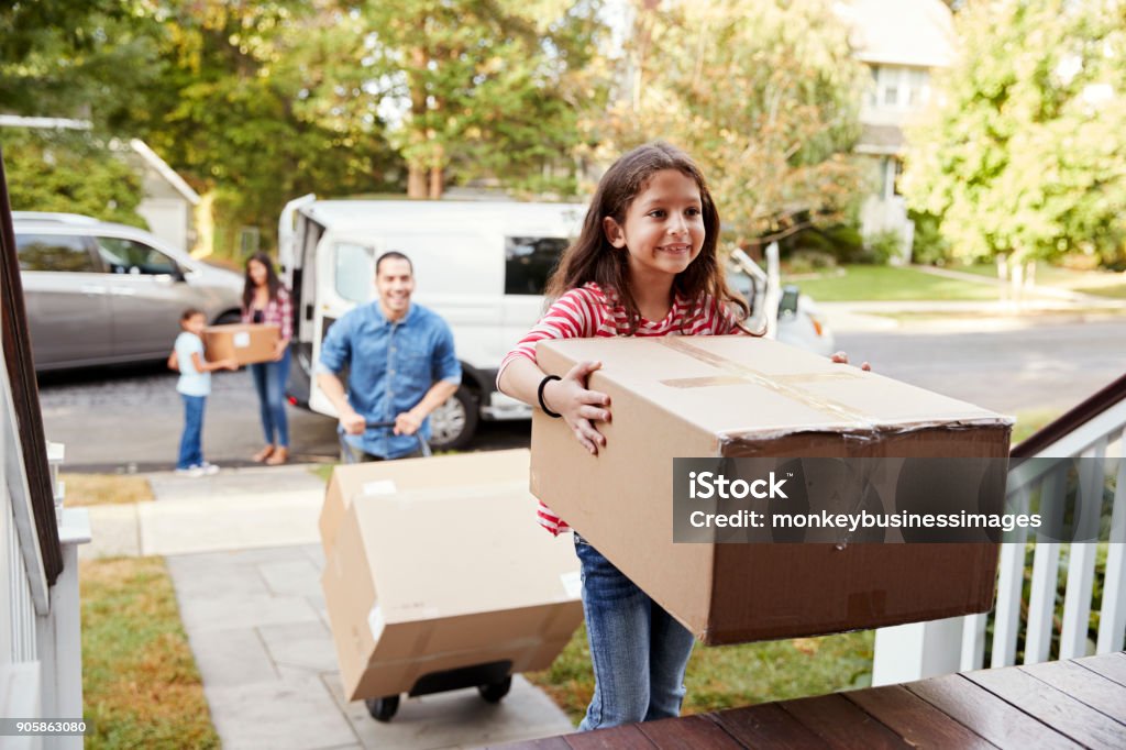 Children Helping Unload Boxes From Van On Family Moving In Day Relocation Stock Photo