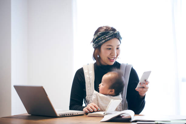 自宅で仕事の赤ちゃんと母親 - スマホ 日本人 ストックフォトと画像