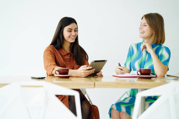 istock Cheerful female colleagues having fun on coffee break discussing ideas for common project  in cafe interior, beautiful women enjoying free time together using digital tablet for browsing information 905870316