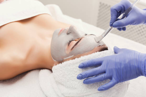 istock Woman gets face mask by beautician at spa 905871112