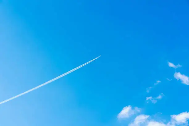 Bright clear blue sky background with diagonal jet plane trace, track, Airplane trace, condensation trails, vapor trails. With copy space