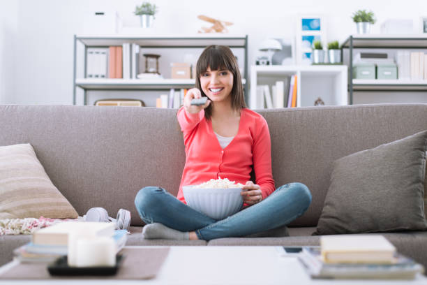 woman watching tv - changing channels imagens e fotografias de stock