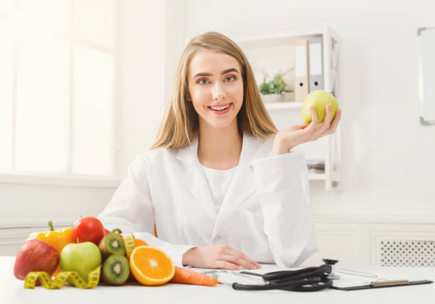 istock Smiling nutritionist woman with apple at office 905883318