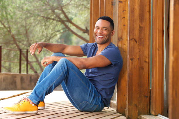 Portrait of handsome young african man sitting outside and smiling
