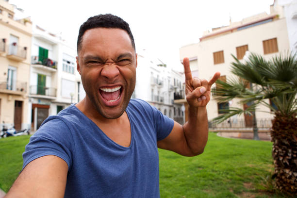 istock Funky young african man making rock and roll hand sign and taking selfie 905883836