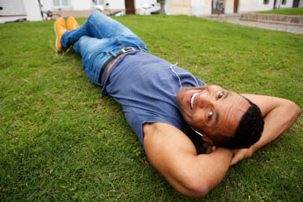 istock Close up happy young african man lying in grass and smiling 905883842