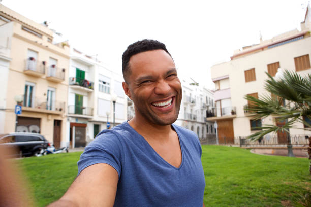 Portrait of cheerful young african man taking selfie outdoors in city