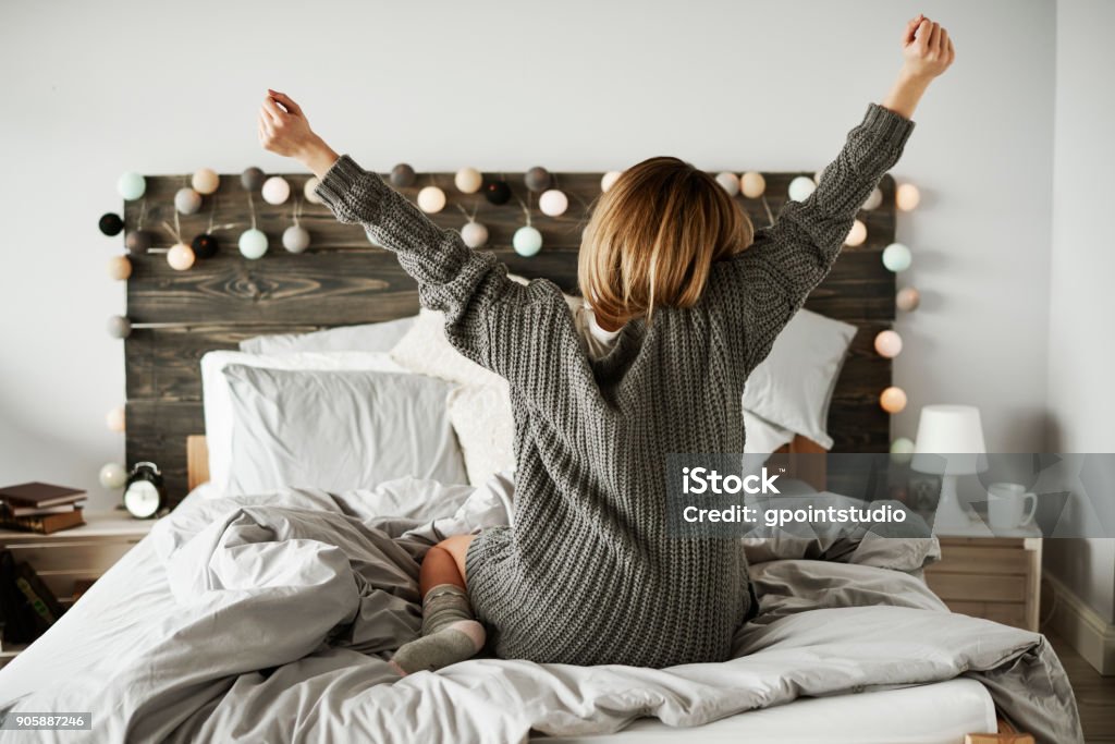 Rear view of woman stretching in her bed Women Stock Photo