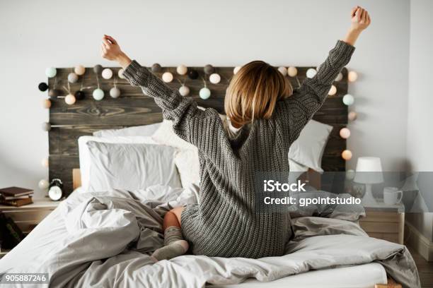 Rear View Of Woman Stretching In Her Bed Stock Photo - Download Image Now - Women, Bed - Furniture, Cozy