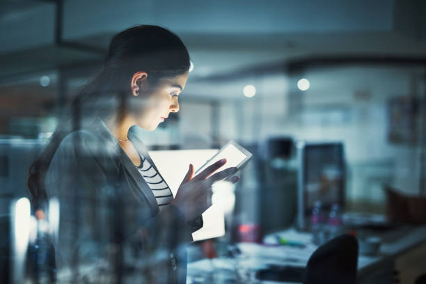 Alone in the office getting work done Shot of a young businesswoman working late in the office office window night stock pictures, royalty-free photos & images