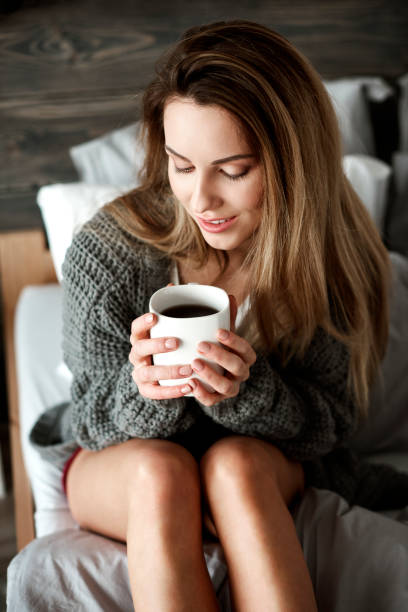 istock Pretty woman with coffee mug on bed 905889806