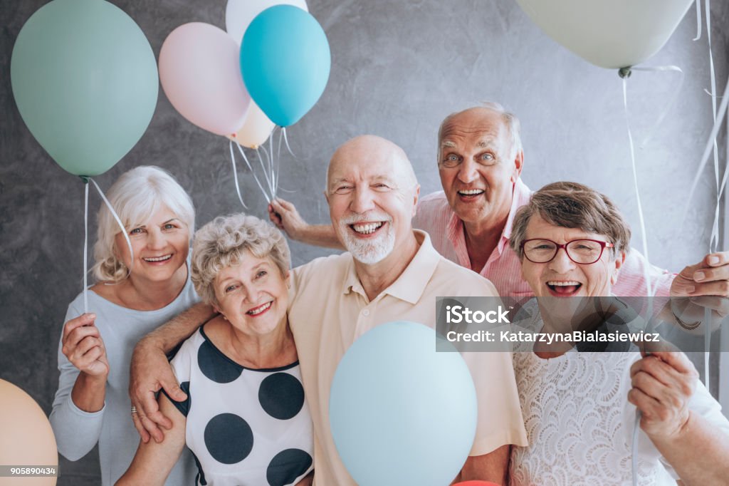 Close-up of excited pensioners Close-up of happy, excited pensioners during a birthday party, holding colorful balloons. Active seniors concept. Senior Adult Stock Photo